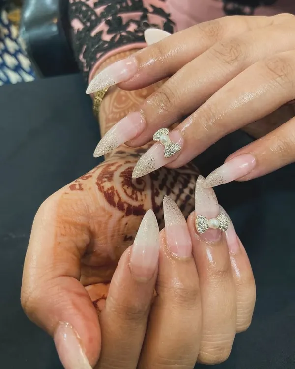Perfect for a wedding or any special occasion. These stiletto nail extensions feature a beautiful glitter ombré effect and are accented with delicate, pearl-centered 3D rhinestone bows for an extra touch of glam.