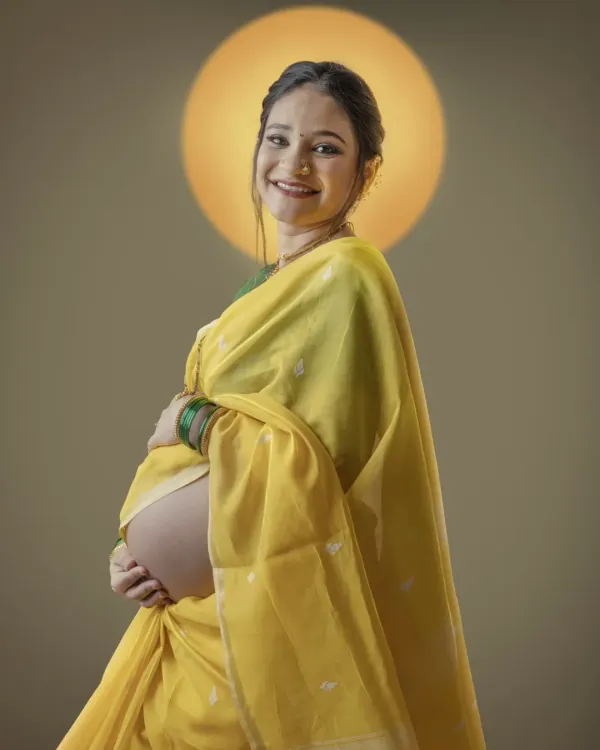 Radiating joy in a traditional yellow saree, this mother to be is a picture of grace. The halo of light behind her symbolizes the divine feminine energy of creating life.