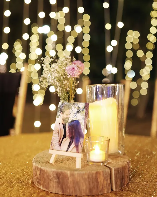 A personalized centerpiece featuring a photo of the couple on a small easel, surrounded by candles and flowers. It's a beautiful way to share your story with guests.