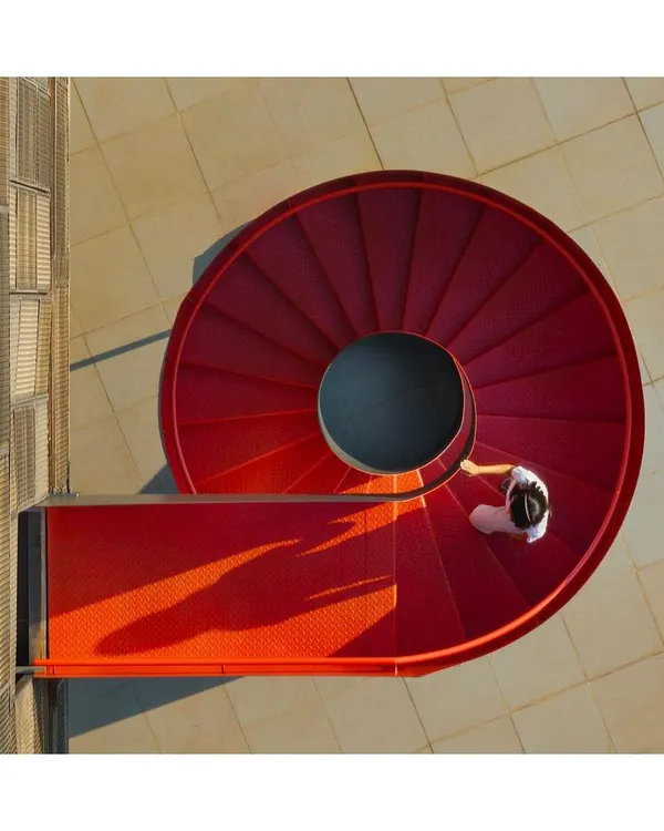 A vibrant scarlet spiral staircase serves as a dynamic vertical connector in a commercial head office. This feature is not just for circulation; it is a sculptural element that brings energy and movement to the building's facade, demonstrating how functional components can become architectural art.