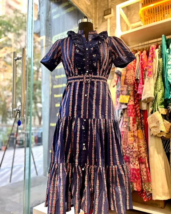 Step back in time with this vintage-inspired dress. It features a beautiful floral and striped pattern, a tiered skirt, and a stunning three-layer ruffle neckline, creating a look that is both romantic and playful.