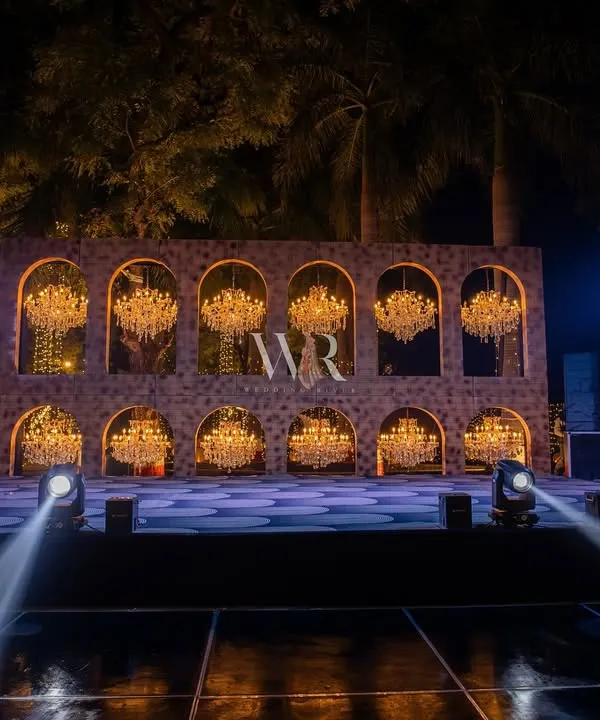 The main stage for a fairytale sangeet. I designed this custom backdrop with two tiers of arched niches, each holding a sparkling chandelier, creating a spectacular wall of light for the performances.