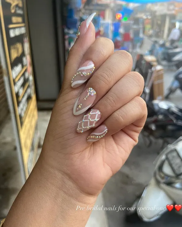 A stunning pre-bridal set for a special client. This design features a nude base with white patterns, intricate rhinestone work, and a textured, sugar-effect nail.
