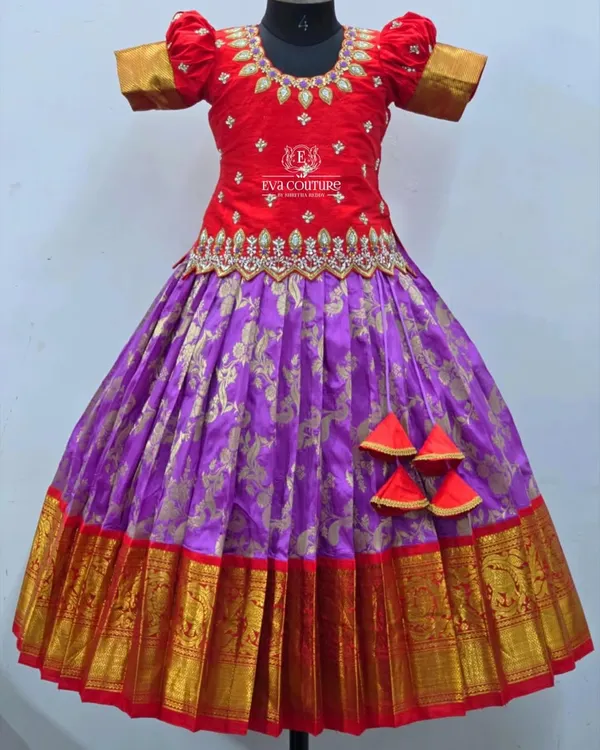 A magnificent Kanchi pattu lehenga in a classic red and purple combination. The red raw silk blouse features intricate stone and zari work, while the purple Banarasi skirt has a wide, traditional temple border.