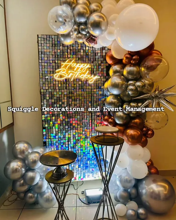 A stunning holographic shimmer wall paired with a 'Happy Birthday' neon sign. The chrome, copper, and white balloon garland adds a touch of modern elegance to this birthday setup.