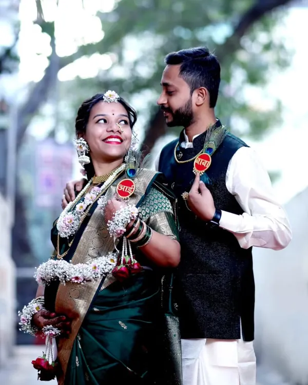 An authentic, happy moment between a couple during their outdoor Dohale Jevan photoshoot. The natural lighting highlights the beautiful details of their traditional attire and floral accessories.