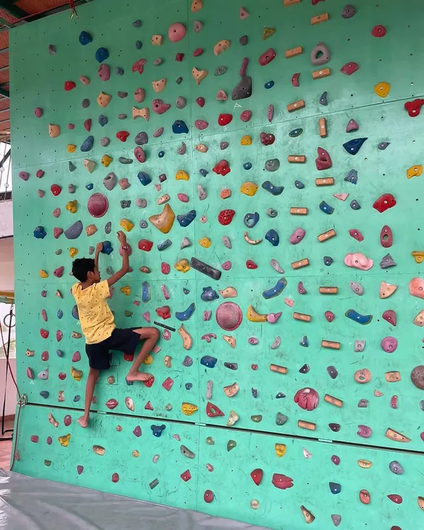 Here, a young climber navigates a bouldering route on our wall. We encourage kids to find their own path, focusing on the process of problem solving and building focus rather than just reaching the top.