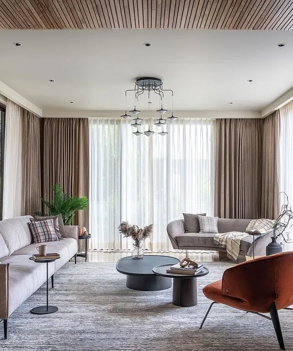 This living space is a perfect example of modern elegance, with a neutral color scheme, clean-lined furniture, and a pop of burnt orange in the armchair for warmth and personality.