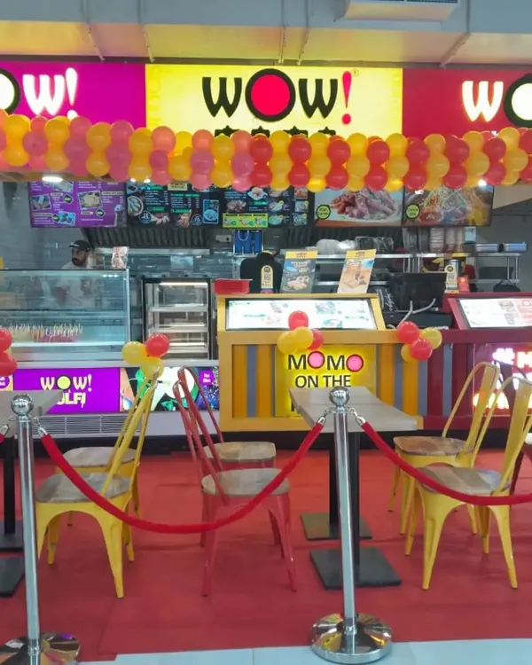A vibrant balloon garland decoration for the grand opening of a WOW! Momo store. The red and yellow balloons match the brand's colors, creating a festive and inviting look for the new outlet.