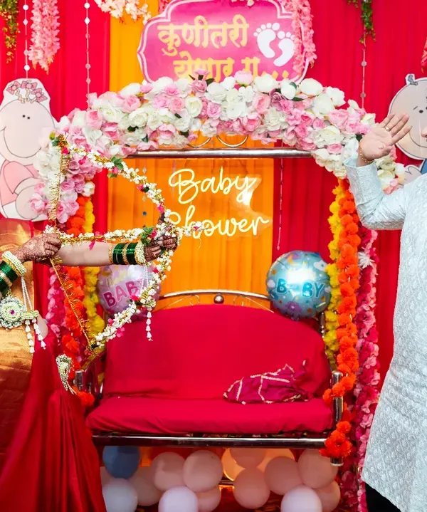 A playful moment during a traditional baby shower, or Godh Bharai. The mother-to-be playfully aims a floral bow and arrow at her husband, a fun ritual that I love to capture.