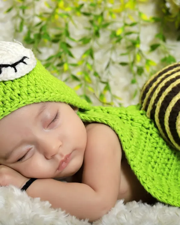A perfect example of a whimsical theme, this newborn is dressed in a cute, hand-crocheted snail costume. I use soft textures and natural backdrops to create a magical setting.