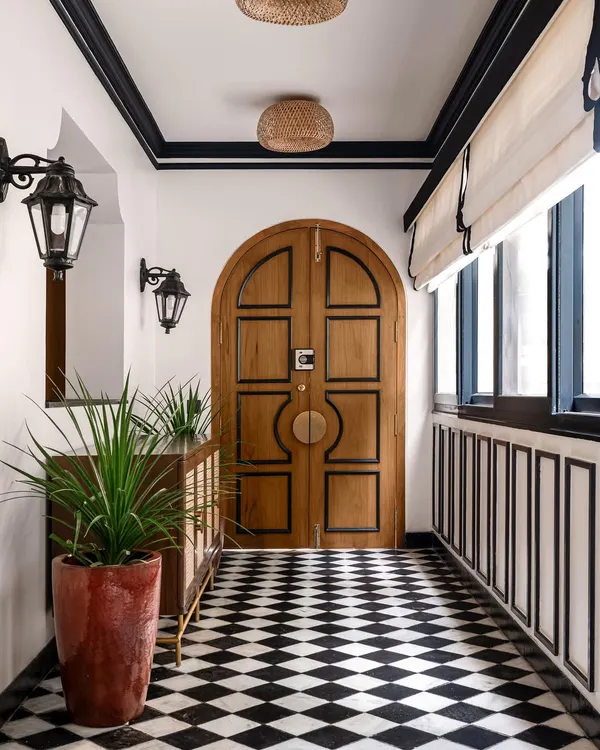 The entryway of our 'Getaway to Galle' project sets a tropical tone with its arched wooden door, checkerboard floor, and traditional lanterns. The space immediately transports you to a breezy, coastal villa.