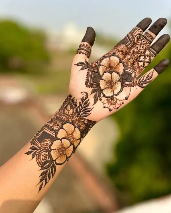 A beautiful and modern floral design on the back of the hand. The use of shading and negative space gives the flowers a realistic, 3D effect.