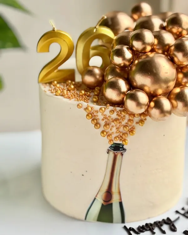 Who needs champagne when the cake’s already popping? This 26th birthday cake features an edible image of a champagne bottle with golden bubbles made of sprinkles and spheres cascading out.