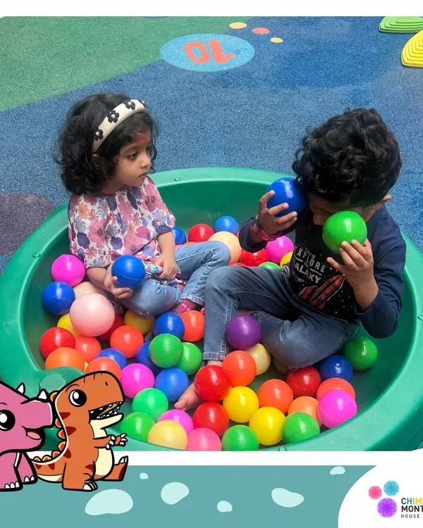 Two friends share a moment in the ball pit. This is more than just play; it's an opportunity for sensory exploration, color recognition, and developing social skills like sharing and communication.