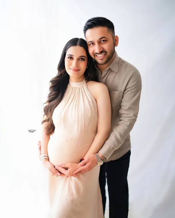 A classic and beautiful family portrait. The expecting couple looks so happy and connected in this bright, light-filled studio shot, creating a timeless memory.