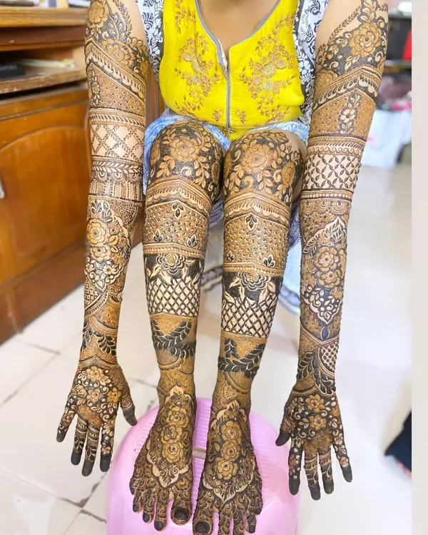 A complete head-to-toe bridal mehendi. This heavy design covers the full arms and legs with a mix of floral patterns, traditional motifs, and intricate checkwork for a truly grand look.