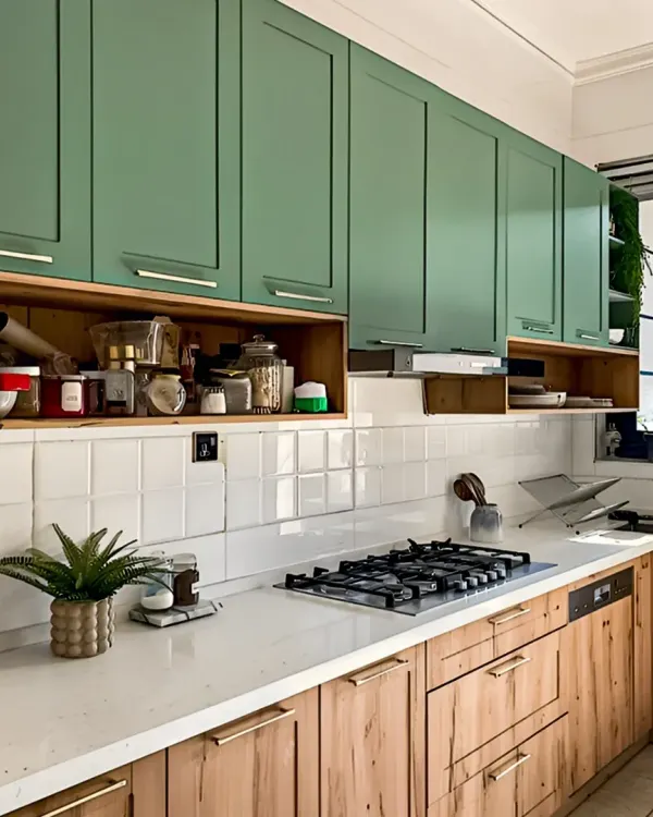 This kitchen features a beautiful two-tone design with sage green upper cabinets and natural wood lower cabinets. The open shelving provides easy access to spices and everyday items.