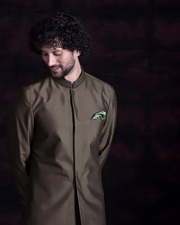This sherwani-style kurta in a deep olive green is a statement in understated elegance. The clean, longline silhouette and mandarin collar offer a refined masculinity, proving that true luxury whispers rather than shouts.
