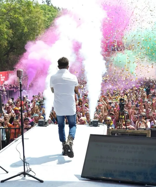 The legendary Sukhwinder Singh on stage, surrounded by a cloud of pink and green colors during the GSC Ranga Rang Holi festival. We combine live music with dynamic special effects for an unforgettable celebration.