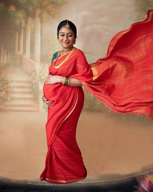 The elegance of a flowing red saree against a painted backdrop. This is the starting point for creating a timeless, painting-style portrait that feels both classic and personal.
