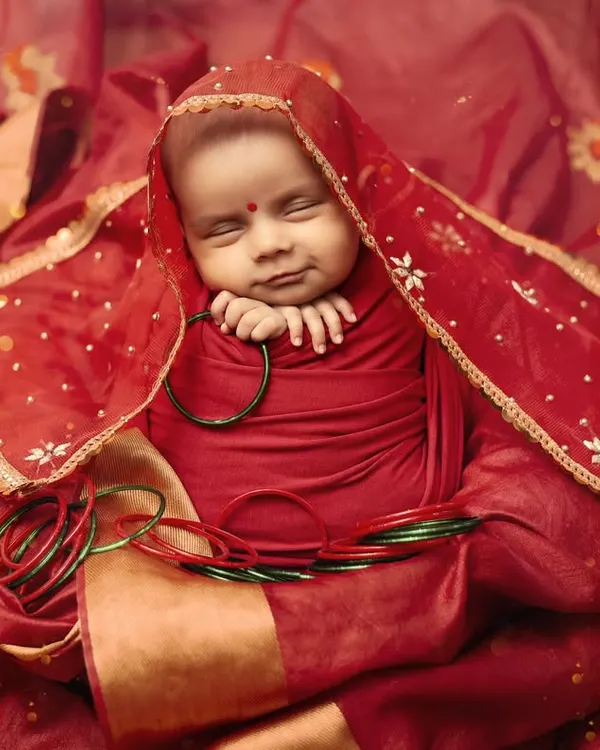 A tiny, peaceful smile on our little devi. This Navratri newborn portrait, with the baby wrapped in red and gold, is a picture of pure serenity.