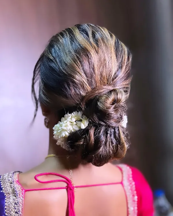 A modern classic, this textured low bun is interwoven with strands of hair and adorned with a simple gajra of jasmine flowers. It's an elegant choice for any occasion, from a wedding to a formal party.