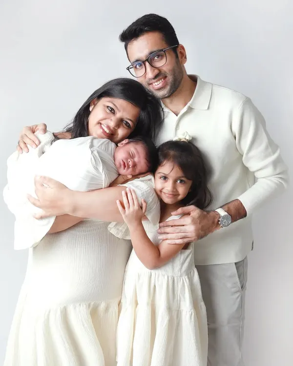 A perfect frame of four. This portrait captures the joy of a growing family, with a new baby brother being welcomed with so much love by his parents and big sister.