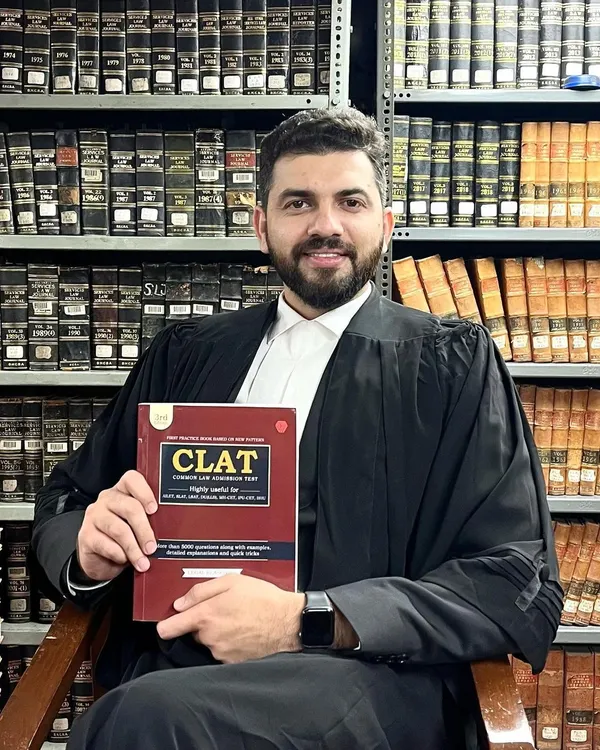 Dressed in my advocate's robes and surrounded by law books, holding the CLAT guide I authored. This image represents my dual commitment: practicing law at the highest level and providing you with the tools to start your own journey. This book is the first step in your legal career.