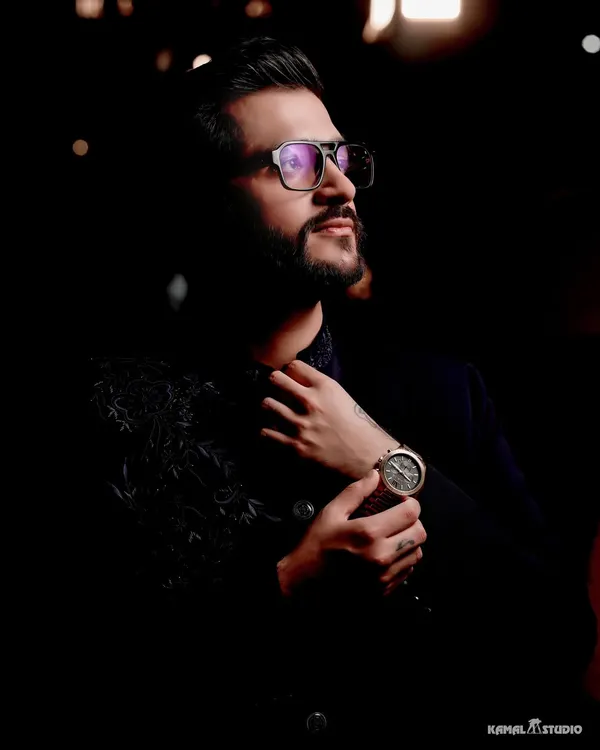 A moody and stylish portrait of the groom, his sharp attire and confident look captured in dramatic lighting.