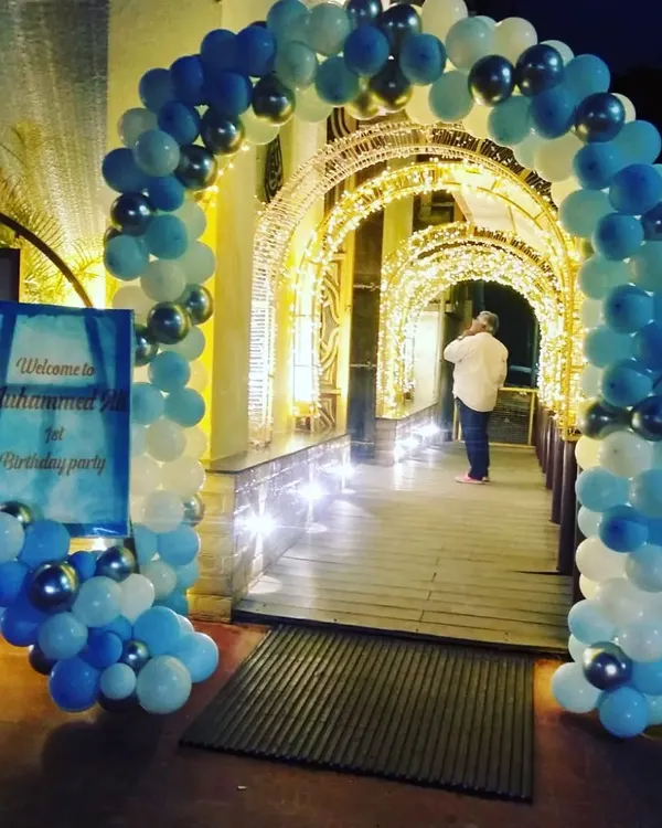 A simple blue and white balloon arch creating an inviting entrance for Muhammed Ali's first birthday party. The arch leads guests through a beautifully lit walkway.