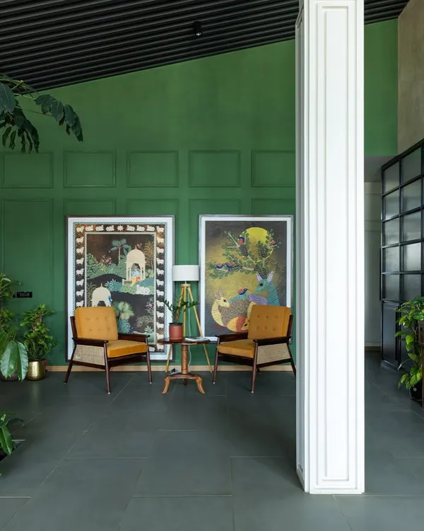 This seating nook in a sales lounge for a senior living community uses a rich green accent wall and warm, comfortable armchairs. The space is designed to feel more like a welcoming living room than a commercial office, fostering a sense of ease and tranquility.