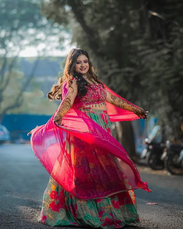 Twirling into her Mehendi function with joy! This bride's look is all about color and celebration, with a fresh, dewy makeup look that complements her vibrant floral lehenga.