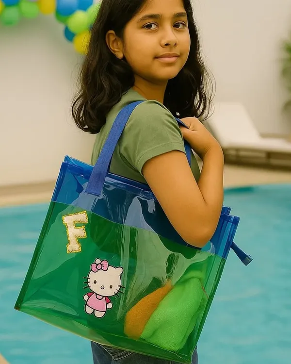 A young girl by the pool with her custom jelly tote bag. The transparent green and blue bag is personalized with her initial 'F' and a Hello Kitty patch, making it a stylish and fun accessory.