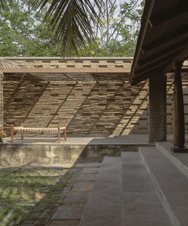 The Kaattu Veedu guesthouse, nestled in the landscape of Hosur, is designed to be in constant dialogue with its surroundings. Here, a local resident seems to agree, finding shade by the patterned earth block walls and traditional stone steps.