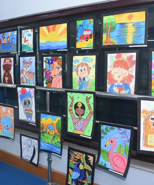 A vibrant display of children's artwork at our Fine Arts Exhibition. This wall showcases a range of subjects, from landscapes to cartoon characters, highlighting the creative freedom we encourage in our kids' art classes.