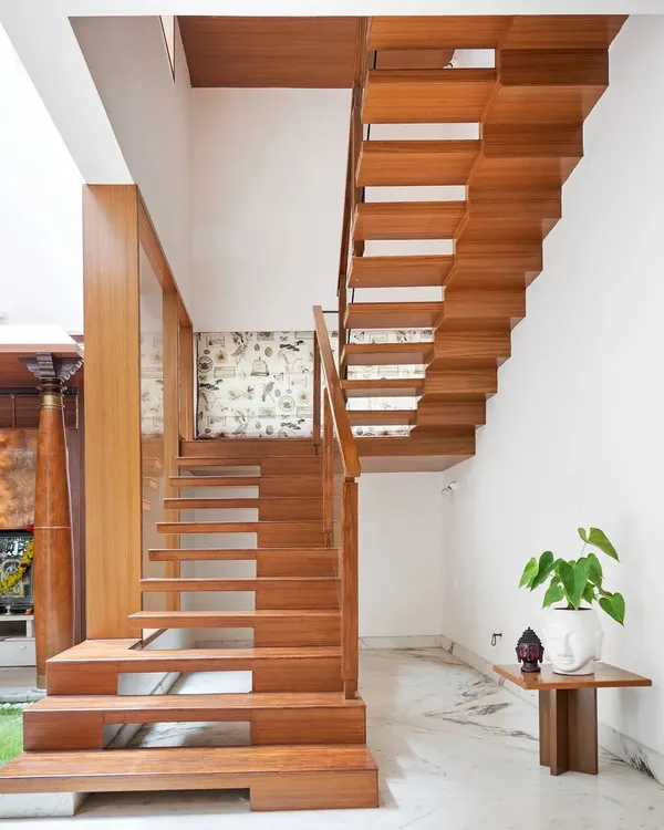 This floating staircase in the Twin Courtyard House is a work of art. The teak wood steps appear to be suspended, creating a sense of lightness, while the wide lower steps provide a casual seating spot near the pooja room.
