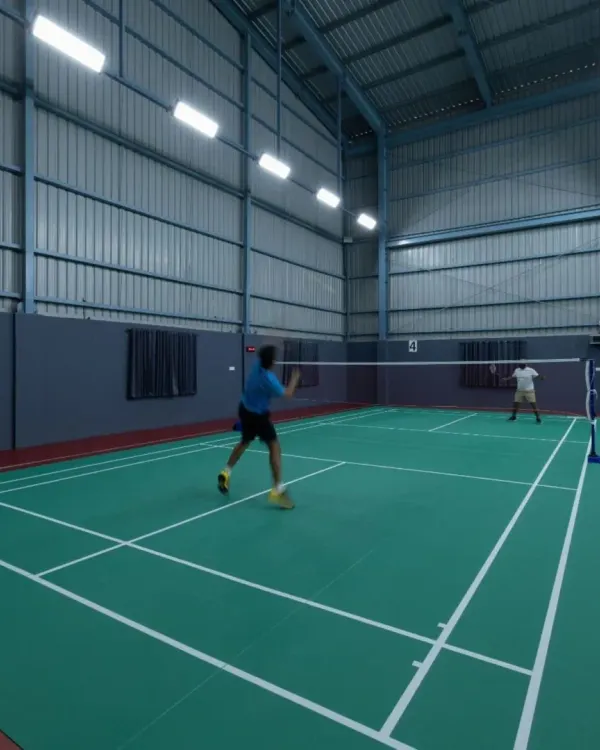 An action shot from inside the GOAT Club, showing the professional-grade courts with anti-glare lighting and sprung wooden flooring designed for optimal play.