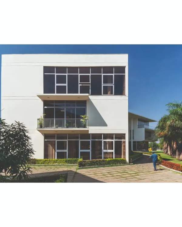 An exterior view of the office block at the Ajax factory campus, showcasing the clean, modernist lines and the integration of the building with the surrounding manicured landscape.