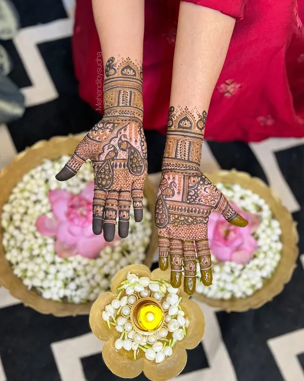 An elegant and traditional design for the mother of the bride. This pattern features beautiful peacock motifs and is set against a festive backdrop of flowers and diyas.