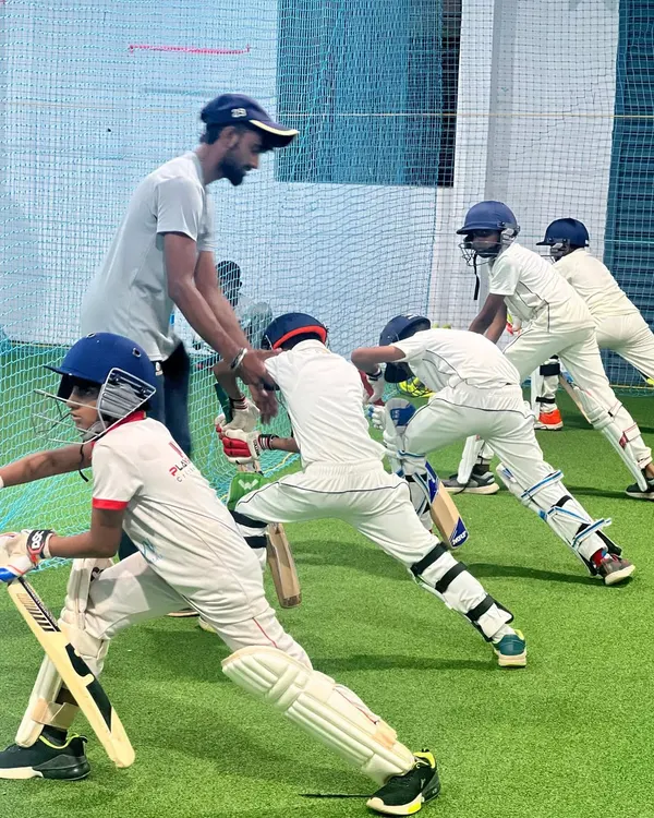 A coach provides hands-on guidance to a line of young batters in our indoor nets. This group drill focuses on establishing a solid, repeatable stance, which is the foundation of good batting.