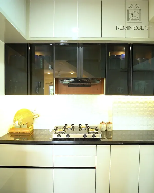 This kitchen showcases a sophisticated two-tone design with handleless glossy white upper cabinets and grey lower cabinets. The design is completed with glass-front display units and a clean, white backsplash, creating a bright and modern aesthetic.