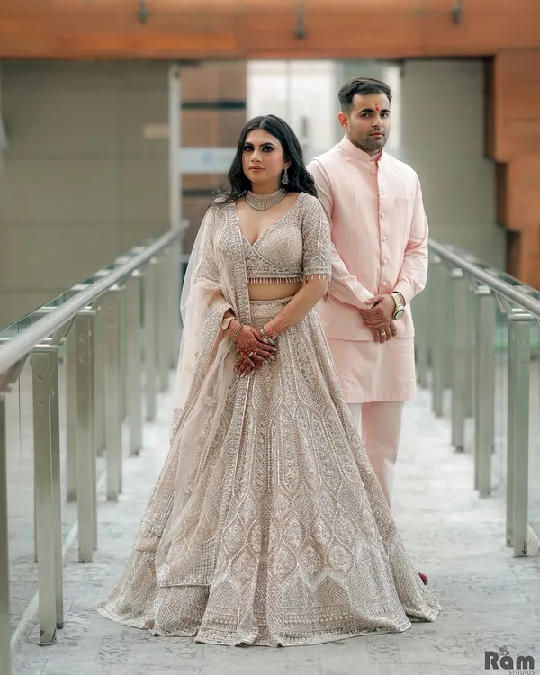 A formal portrait from an engagement ceremony. The couple's coordinated pastel outfits and the modern architectural background of the venue create a sophisticated and elegant look.