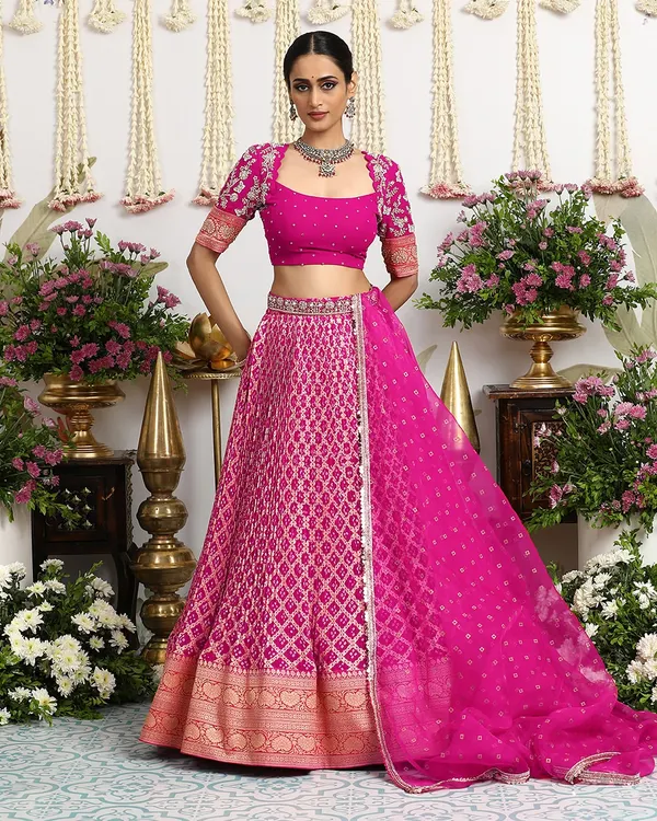A vision in fuchsia, this Bandhani lehenga from our Kesariya collection is a celebration of vibrant color and heritage craft. The full ensemble, complete with a Banarasi border and embellished blouse, is perfect for the modern bride.