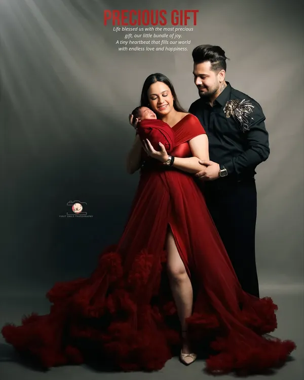 This is the magic of new life. In this studio family portrait, we created a dramatic and elegant look with a flowing red gown to celebrate the arrival of their precious gift. The soft lighting highlights the tender moment between the parents as they hold their newborn.