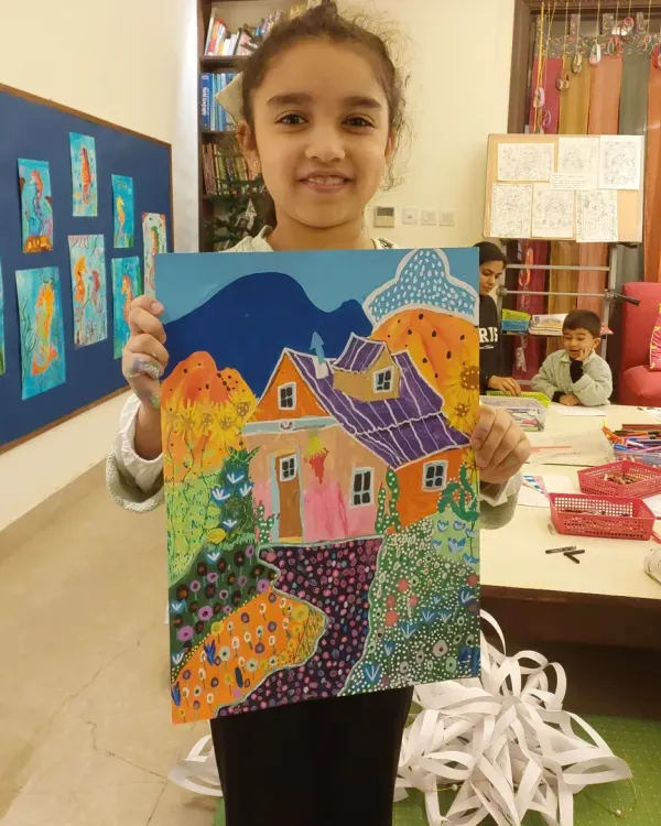 Happiness is a finished work of art. This 8-year-old student proudly displays her colorful house painting, done with acrylics on paper.
