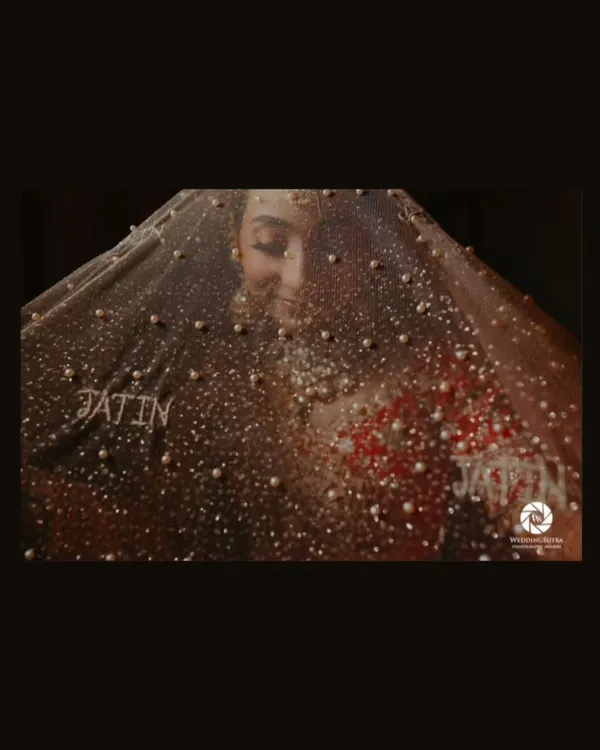 A creative and award-nominated bridal portrait, with the bride's face partially obscured by a pearl-studded veil that has the groom's name on it.