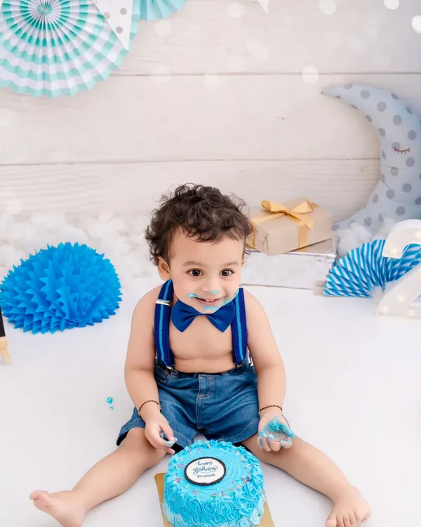 A happy birthday boy enjoying his very own blue cake. The pure delight on his face is what makes cake smash photography so special.