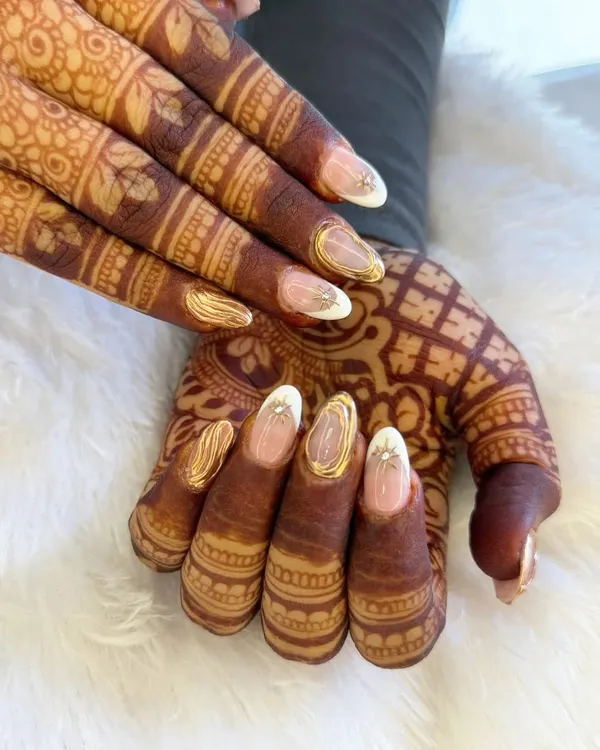 A stunning example of bridal nails designed to complement traditional henna. This set features a clean base with intricate gold detailing and a touch of sparkle, creating a look of pure elegance.
