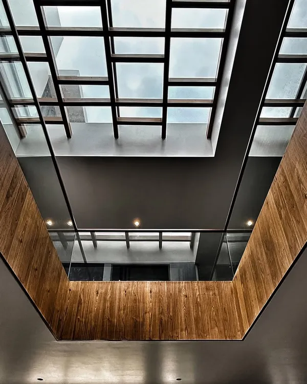 Looking up through a central atrium at the Drishya project. The gridded skylight and wood-clad walls create a powerful architectural statement while drawing natural light deep into the home.